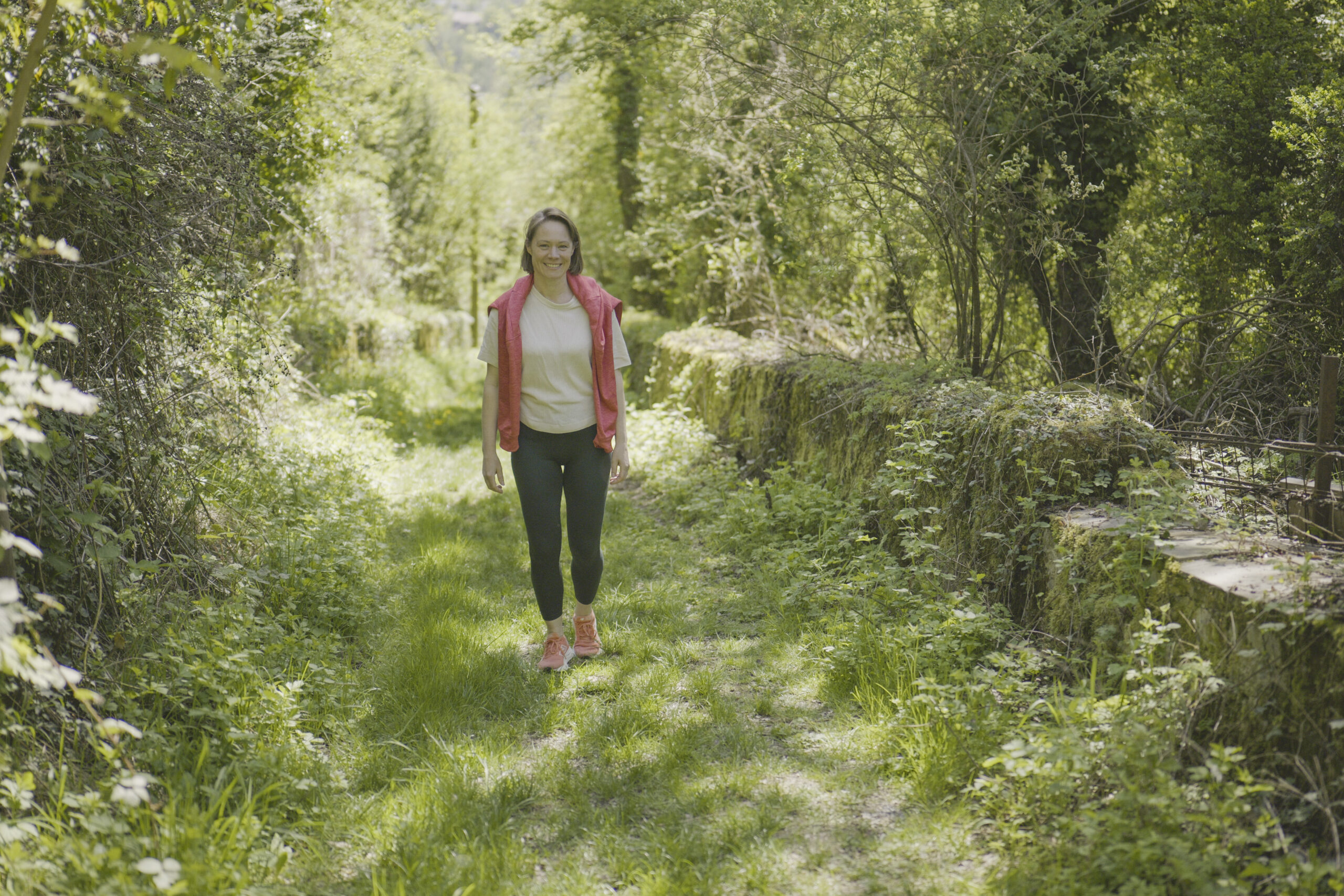 Sonja Huber geht einen Weg durch grünen Wald entlang